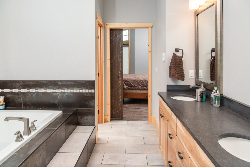 Master bathroom with recessed bathtub, double sink and hallway to bedroom