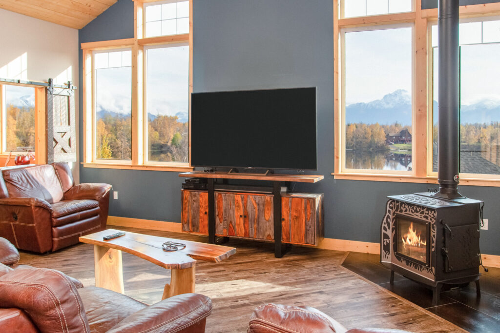 New, rustic living room with TV stand, small fireplace, and view of mountains through windows