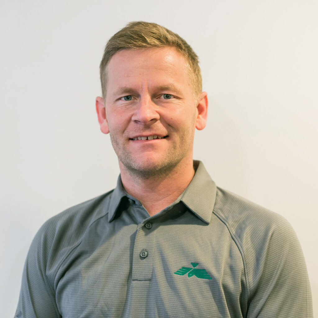 Smiling Falcon Alaska employee wearing branded Falcon Alaska polo shirt