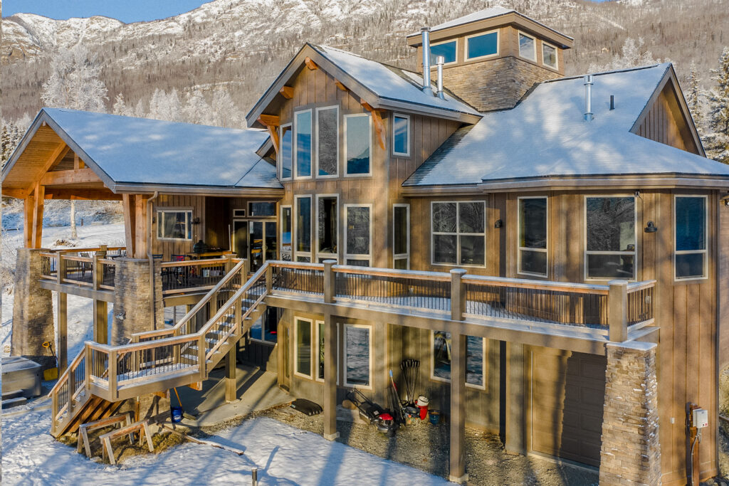 Backside of a 3-story home with wrap-around raised deck  in the snow