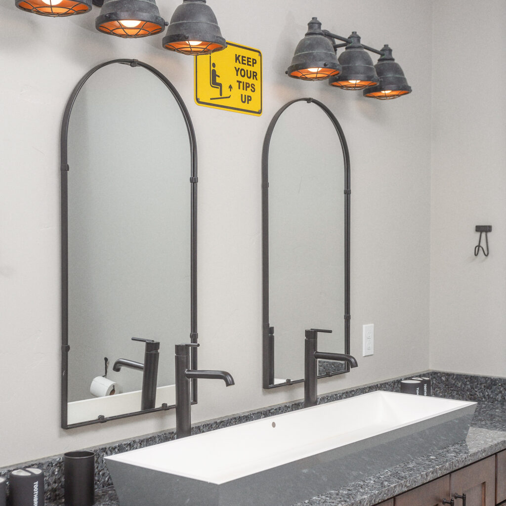 Bathroom with connected double sink, two mirrors, and metal light fixtures above