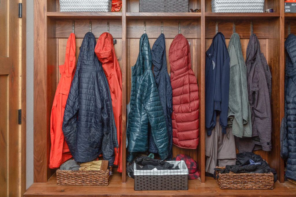 Mudroom coat racks with several colored coats hanging