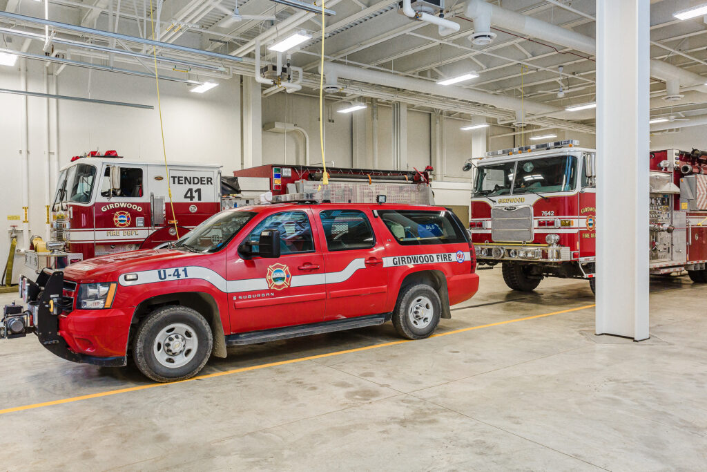 2 firetrucks and a fire marshall SUV parked in a fire station