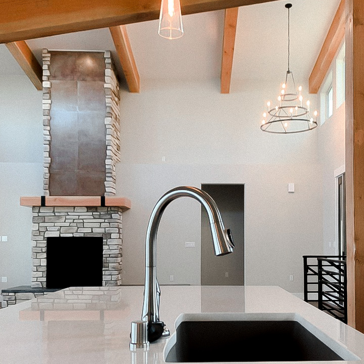 Kitchen sink of modern custom built home in Alaska with fireplace in background