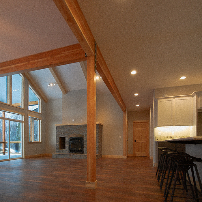 Living room of a house with high slanted ceiling and 4 metal stools at a kitchen island