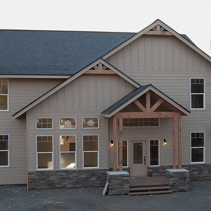 Front exterior of a new home with tan siding and built-out entryway roof