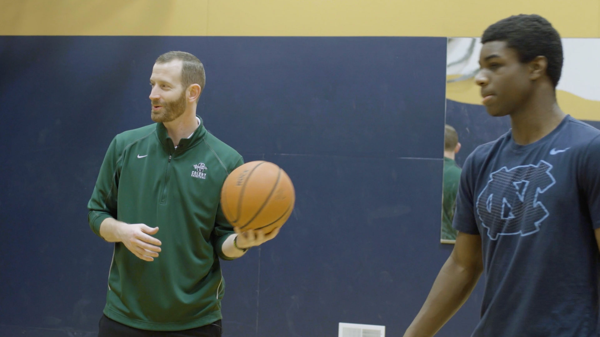 Basketball coach smiling with younger player walking past