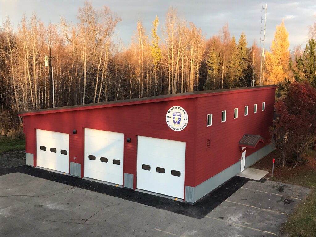 Red fire station with slanted roof and 3 garages for firetrucks