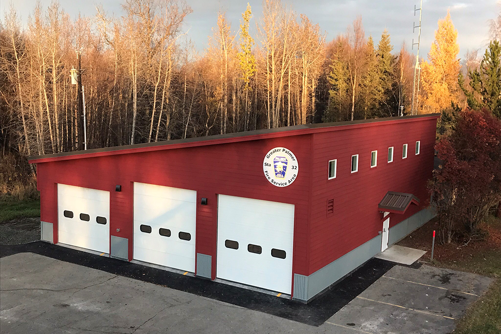 Red fire station with slanted roof and 3 garages for firetrucks