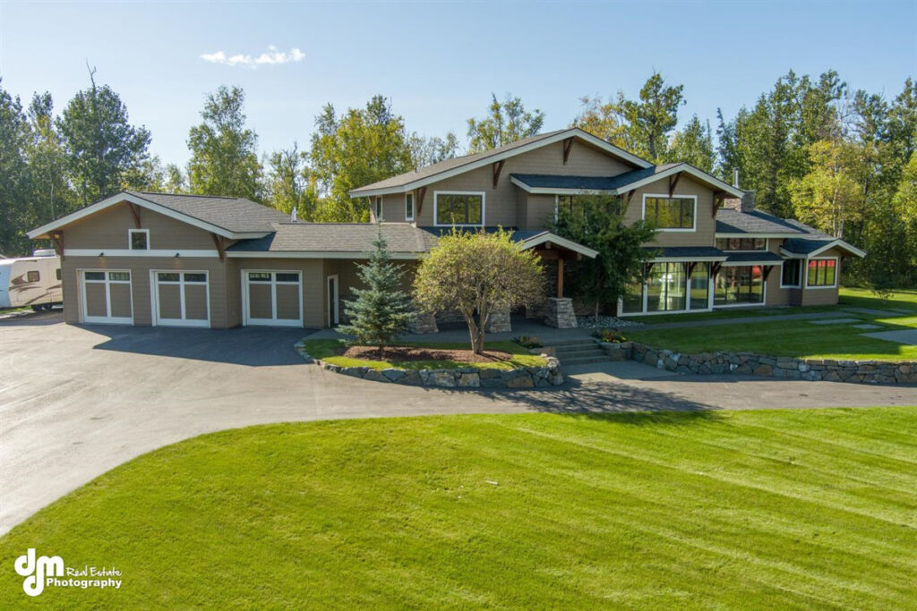 High angle of a new, large house with woods behind it in the sun