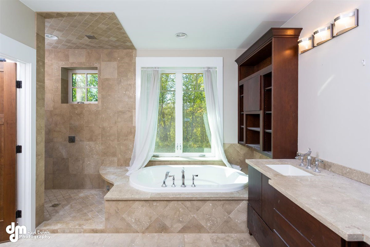 Bathroom of custom built home with bathtub, shower, sink & large window