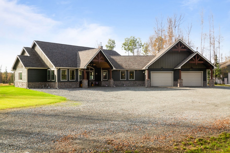 Exterior of a new gray building with attached 2 car garage and gravel parking area