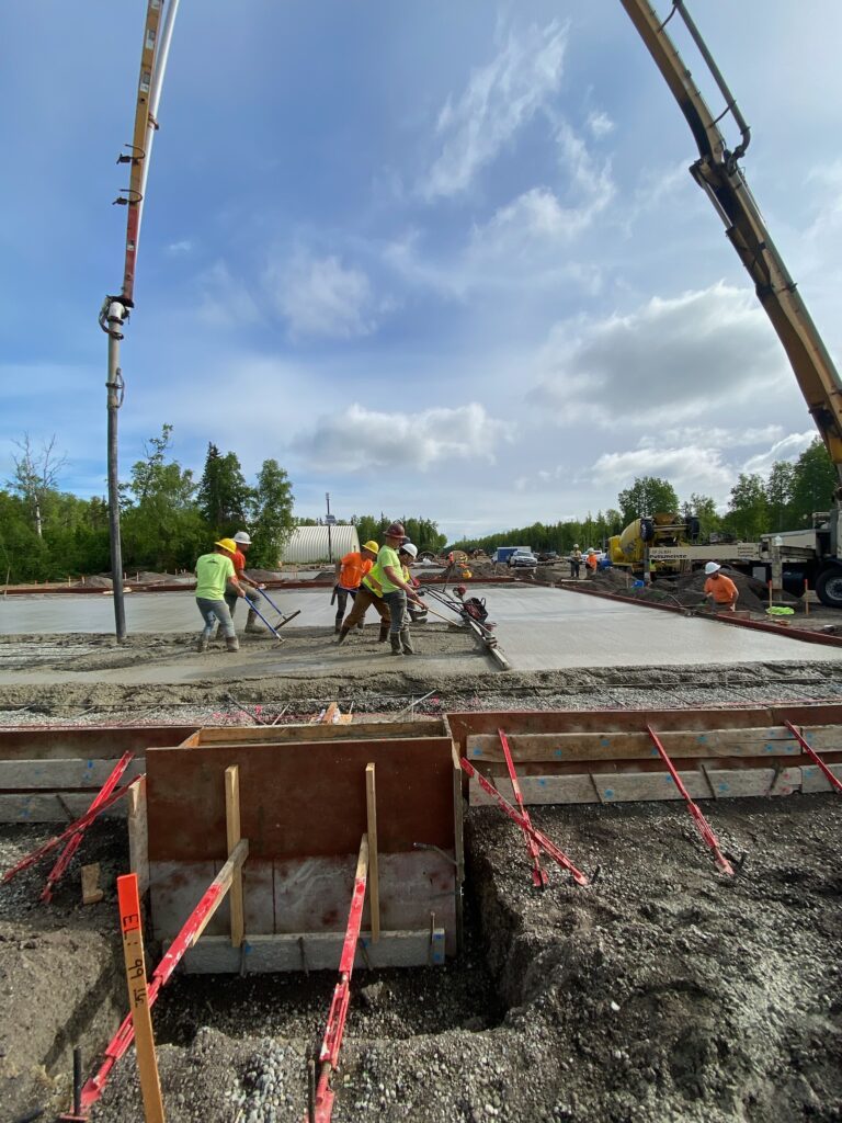 Employees lay concrete for building foundation
